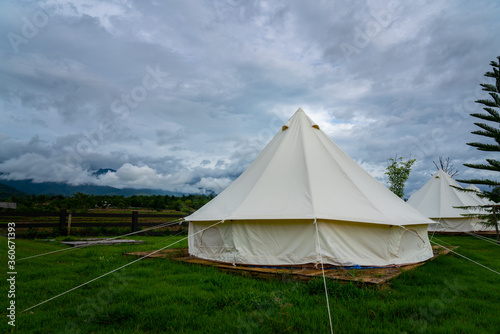 Canvas dome tent or Wigwam camping room at rural location with natural environment such as mountain valley, greenery garden and cloudy sky. Recreation outdoor activity photo concept. © Nattawit