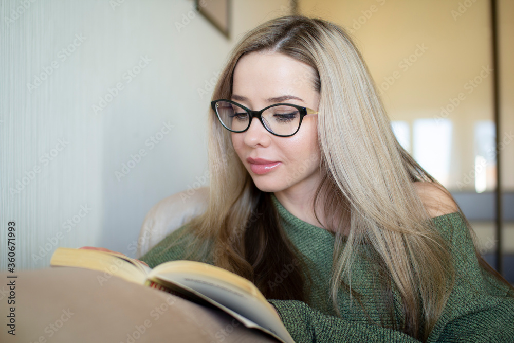 A pretty young woman is happy to read a book at home. A pretty young woman is happy to read a book at home.