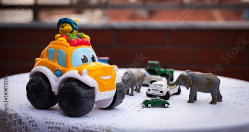 Randomly placed toy cars and toy animals are on the round table over a white blanket. Early childhood concept. Creativity and child plays. © Caner