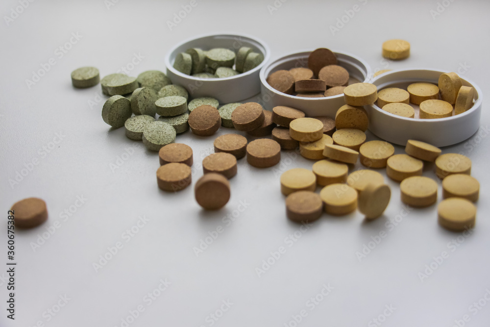 Supplements in containers are scattered on the table close-up. White background. Vitamins and food additives help take care of health, have natural plant components and healthy nutrients. Supplements in containers are scattered on the table close-up. White background. Vitamins and food additives help take care of health, have natural plant components and healthy nutrients.