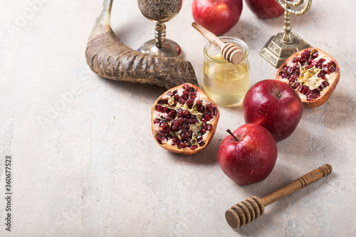 Rosh hashanah - jewish New Year holiday concept. Traditional symbols: Honey jar and fresh apples with pomegranate and shofar-horn,  on a concrte   background. Copy space for text. View from above photo