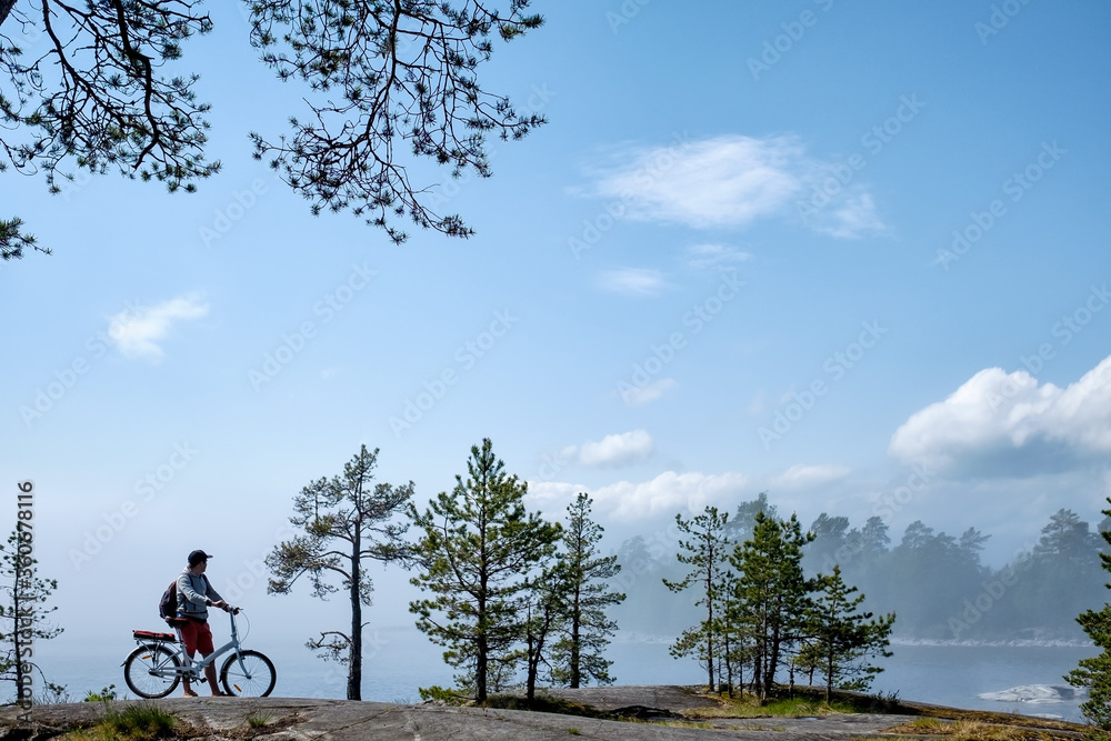 Fototapeta premium Young men riding a bicycle on bike trail at the lake in the morning. Active people spending time outdoors