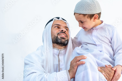 Arabic muslim father holding his son on his shoulder