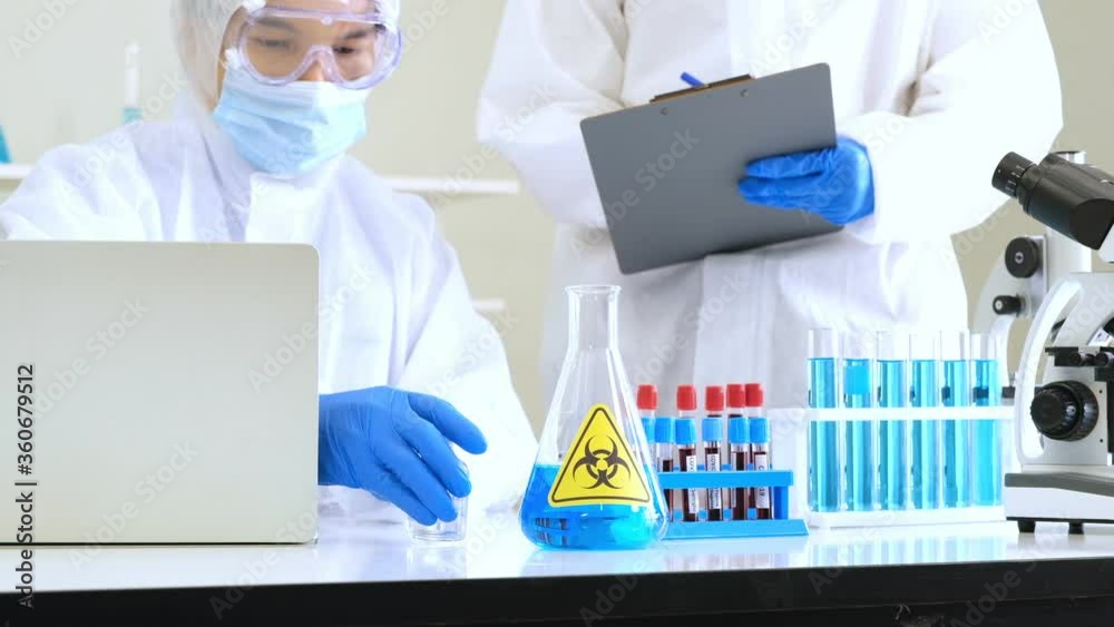 Researchers picked up bottle of covid-19 vaccine and discuss with assistant about test results at laboratory. Researchers picked up bottle of covid-19 vaccine and discuss with assistant about test results at laboratory.