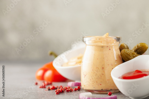 Thousand Islands sauce and ingredients - cucumbers, onions, paprika, ketchup and mayonnaise in bowls on the table. American cuisine, dip for burgers and meat. photo