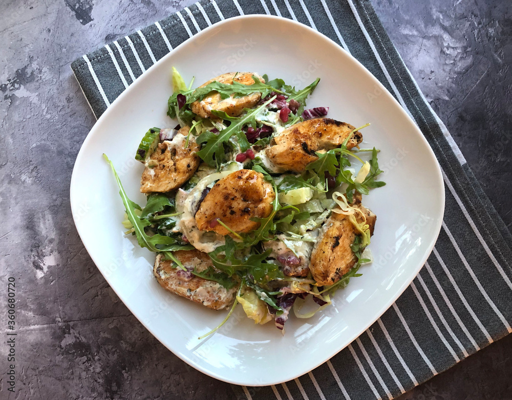 Grilled chicken fillets strip on mixed greens salad and yogurt dressing. Classic summer dish. Grilled chicken fillets strip on mixed greens salad and yogurt dressing. Classic summer dish.