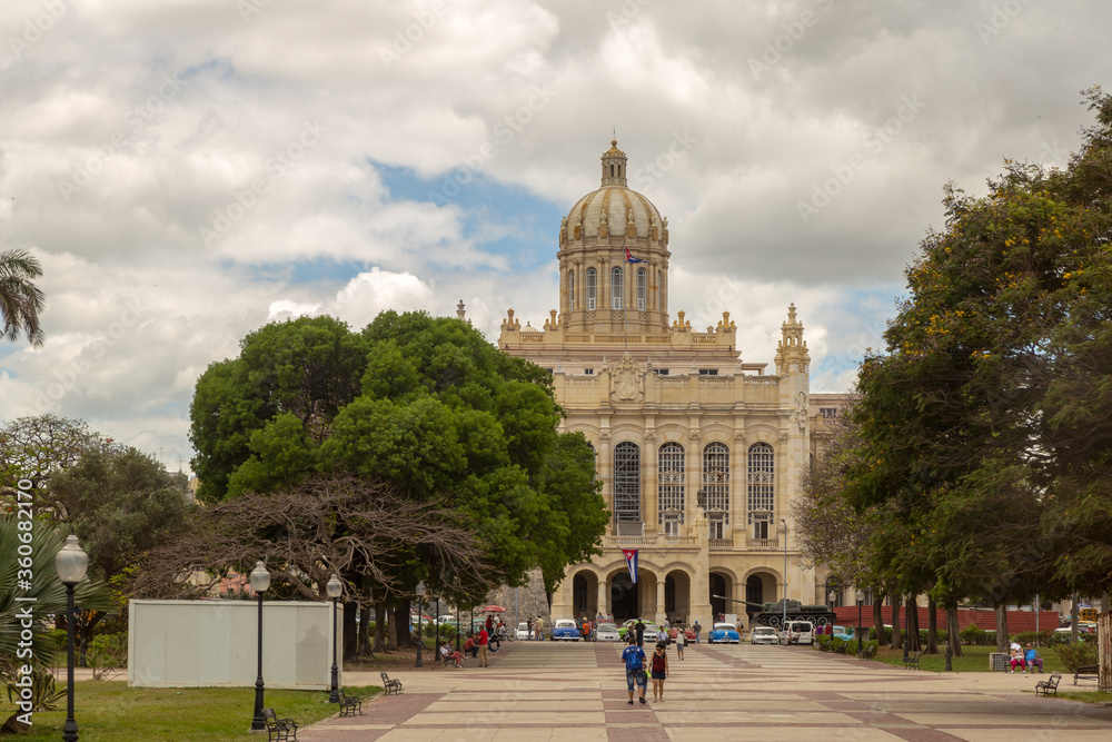 HAVANA, CUBA - CIRCA 2017: View of the Museum of the Revolition, in Havana Cuba on a background of blue sky with clouds. Tourists enjoying the weather having a walk.