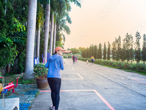 Young fitness woman running at tropical park in the evening photo