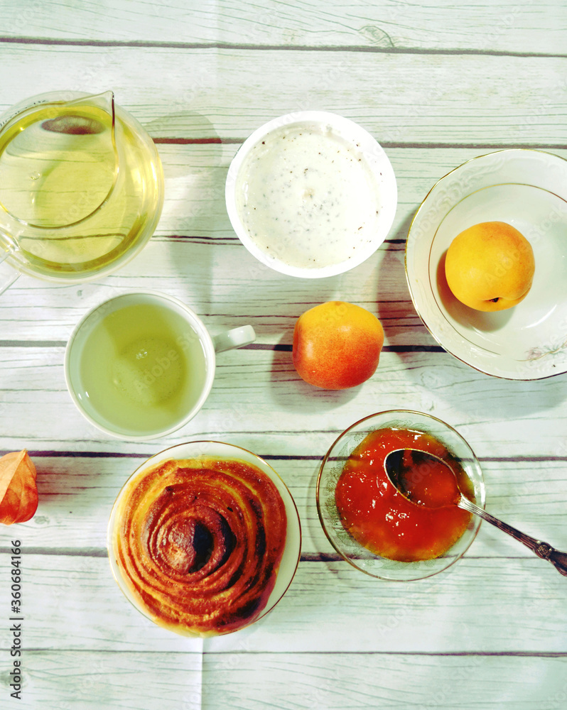 Healthy breakfast on the table with green tea cup, glass teapot, fresh apricots, apricot jam, twist of bread, skyr. Healthy life style. Food still life. Top view Healthy breakfast on the table with green tea cup, glass teapot, fresh apricots, apricot jam, twist of bread, skyr. Healthy life style. Food still life. Top view