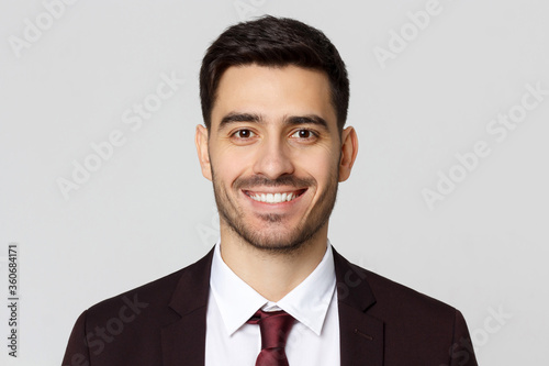 Close up portrait of smiling business man standing against gray background