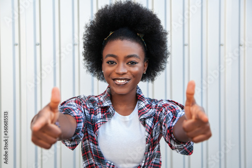Positive emotions and people concept - portrait of attractive happy young black african american woman pointing fingers. Over grey background. Lifestyle in city.