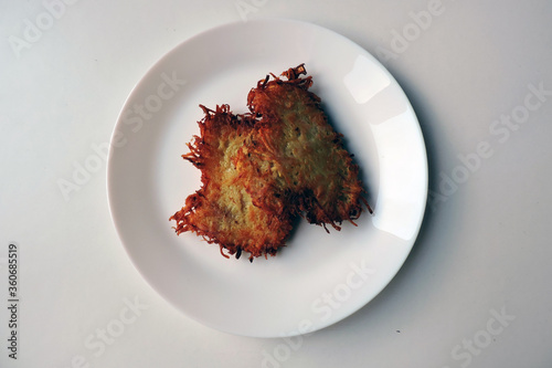 Two crispy fried potato cakes served on a white plate, white background photo