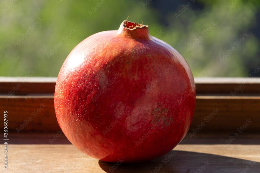 Ripe pomegranate fruit on a wooden windowsill
