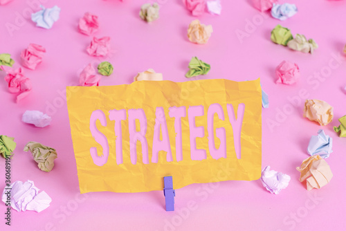 Handwriting text writing Strategy. Conceptual photo action plan or strategy designed to achieve an overall goal Colored crumpled papers empty reminder pink floor background clothespin photo