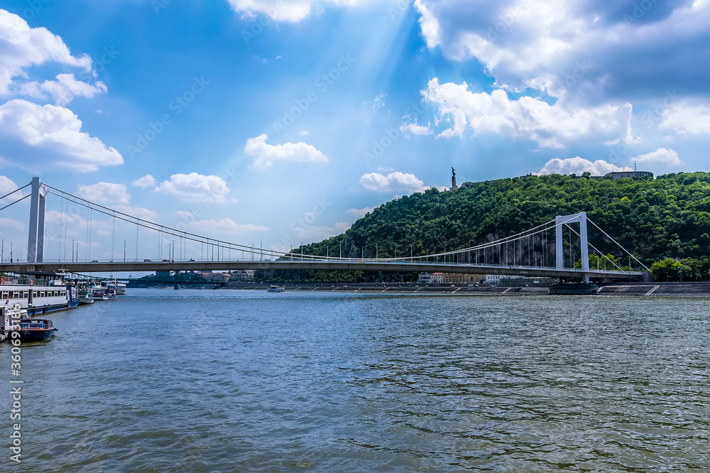 A view across the River Danube in Budapest towards the Elizabeth Bridge and the Liberty statue in the far distance during summertime