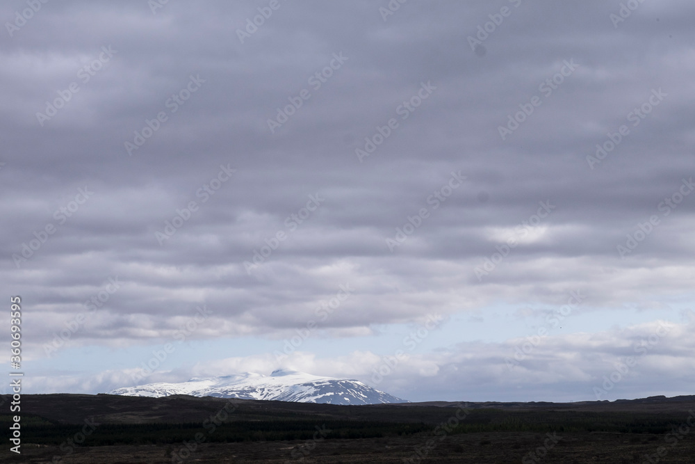 A snowy mountain in the Golden Circle on Iceland near Geysir with heavy clouds above a blue sky