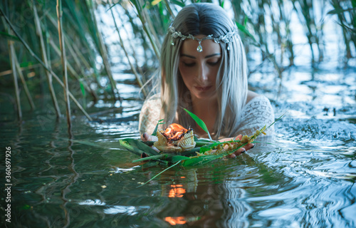 Fototapeta Naklejka Na Ścianę i Meble -  Mermaid girl bride in white dress in lake. Fantasy girl. Mysterious scene. Witch standing in the river and practice witchcraft. Fairytale
