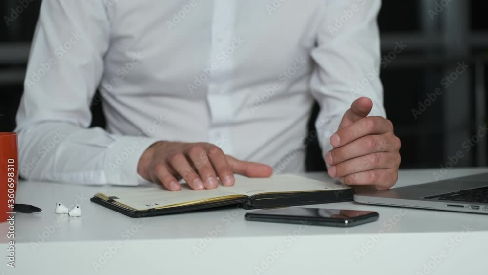 A young brutal man in an office with a night city puts down his headphones and starts working A young brutal man in an office with a night city puts down his headphones and starts working