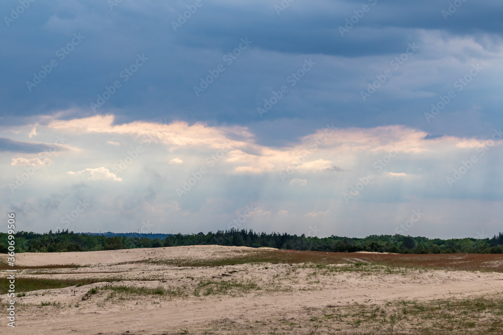 Desert in spring distant view on sand dunes near forest with epic dark sky. Kitsevka desert hilly sands in Ukraine, Kharkiv region landscape
