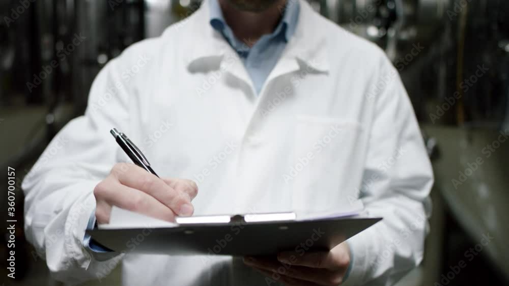 A mature factory male worker is making a list of all requirements for a product. A front view slow motion close up A mature factory male worker is making a list of all requirements for a product. A front view slow motion close up