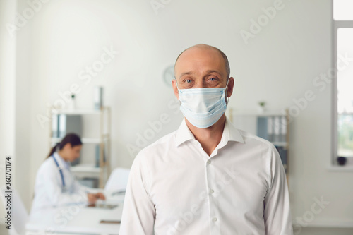 Senior man wearing protective mask on visit to doctor at hospital  blank space. Patient and medical specialist at clinic