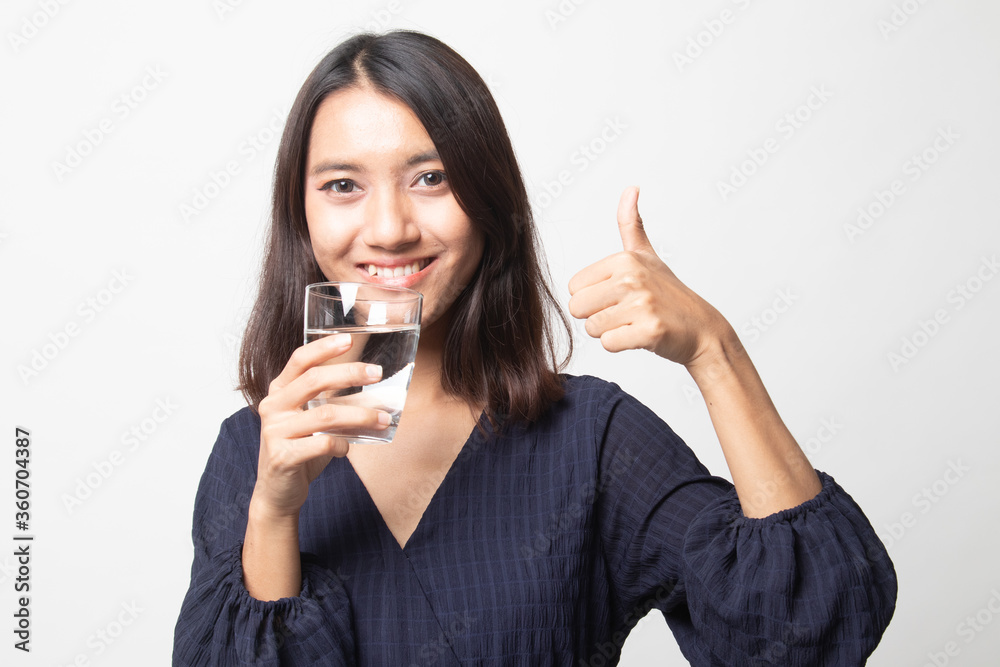 Young Asian woman thumbs up with a glass of drinking water. Young Asian woman thumbs up with a glass of drinking water.