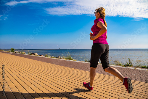 middle-aged woman running by sea shore