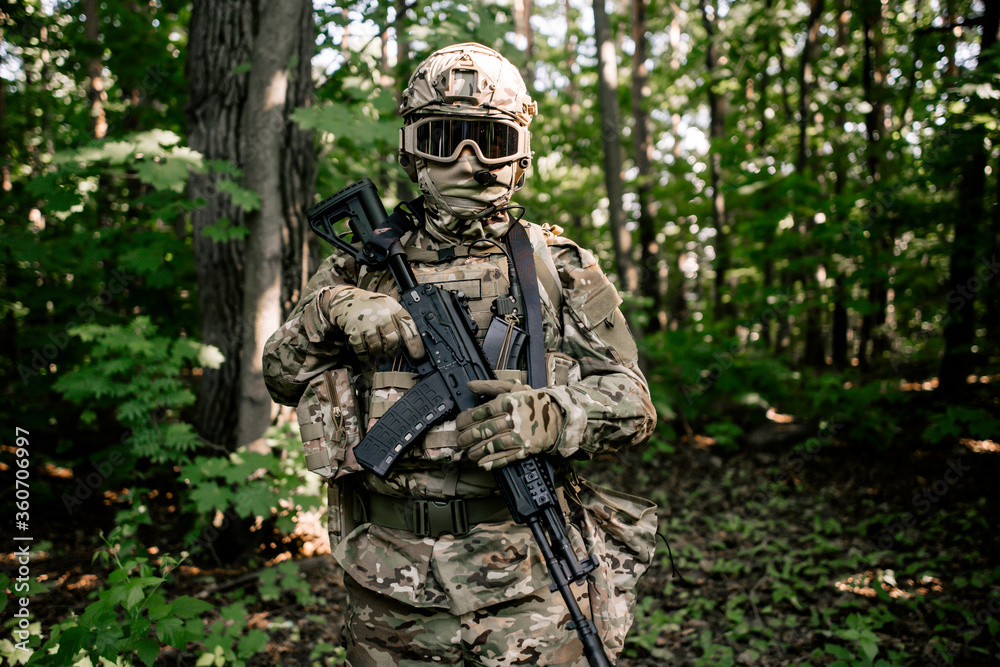 Portrait of a military soldier with a weapon in his hands in the forest thicket