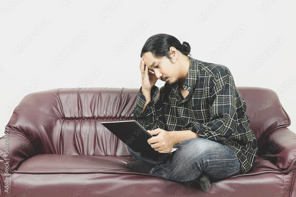 long hair asian men working on laptop computer sitting on sofa