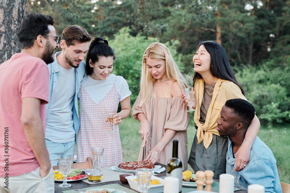 Obraz premium Laughing Asian girl embracing African young man during gathering of friends