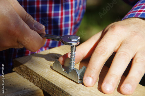 A carpenter with a wrench in hand tightens the screw
