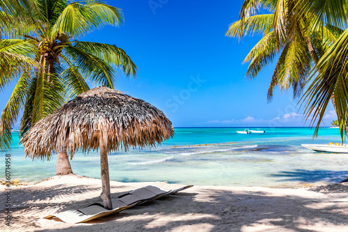 Fototapeta Naklejka Na Ścianę i Meble -  Straw umbrella on the tropical beach with white sand, ocean and palms. Vacation travel relaxation background