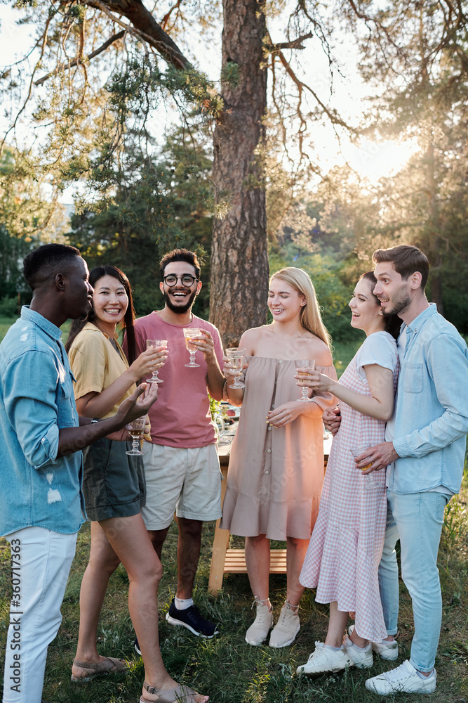 Young cheerful men and women of various ethnicities cheering up with drinks Young cheerful men and women of various ethnicities cheering up with drinks