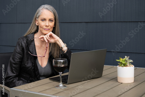 Beautiful mature woman working outside on a laptop