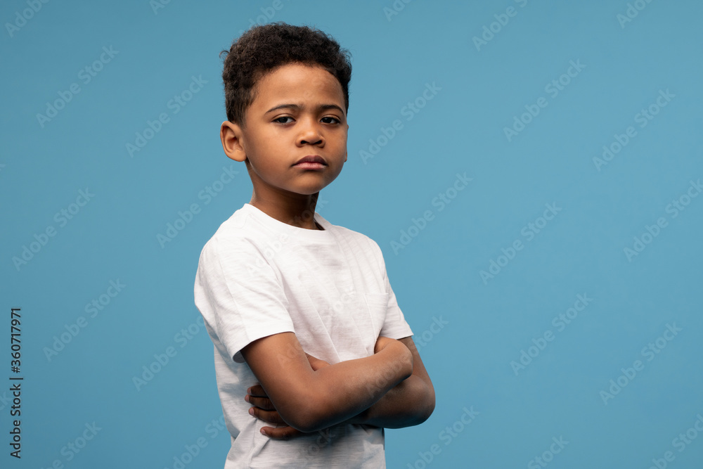 Serious or offended cute little boyin white t-shirt crossing his arms on chest Serious or offended cute little boyin white t-shirt crossing his arms on chest