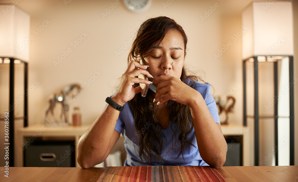 stressed filipina nurse taking phonecall at home stressed filipina nurse taking phonecall at home