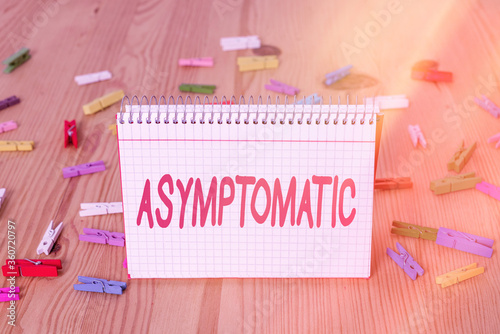 Handwriting text writing Asymptomatic. Conceptual photo a condition or an individual producing or showing no symptoms Colored clothespin papers empty reminder wooden floor background office photo