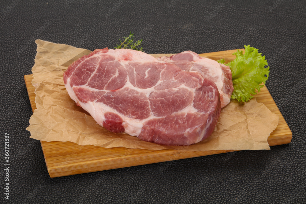 Raw pork steak over wooden board Raw pork steak over wooden board