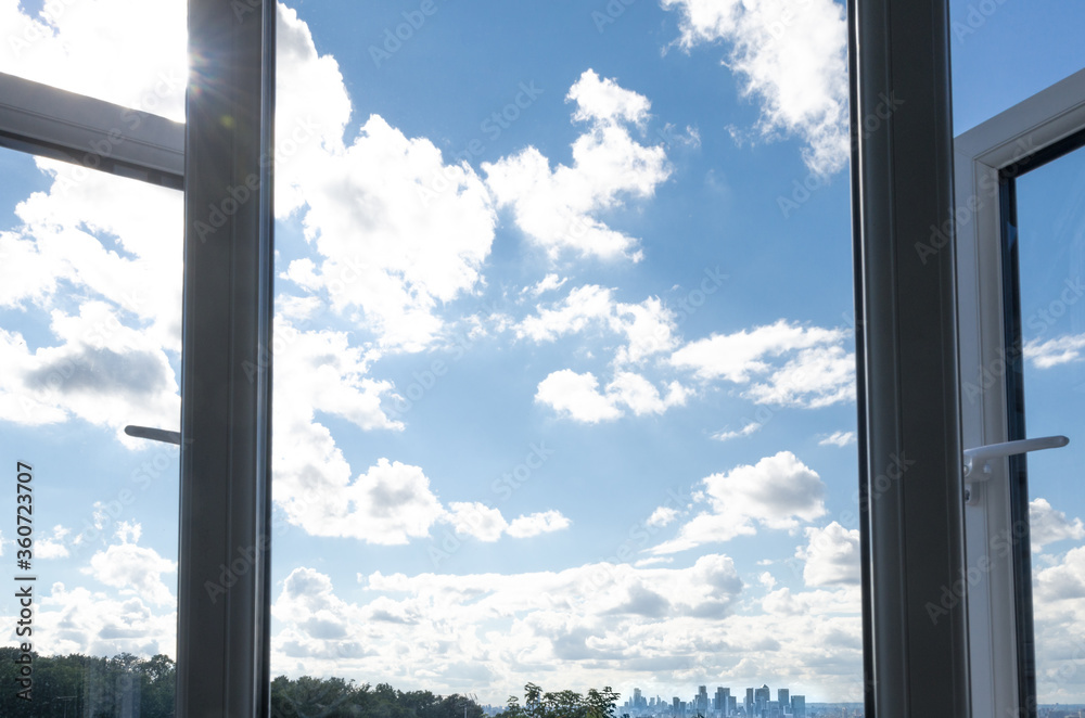 Window and sky in summer with distant view of Canary Wharf skyscrapers, London Window and sky in summer with distant view of Canary Wharf skyscrapers, London