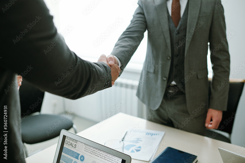 Handshake of two elegant business partners or hr manager and applicant over desk