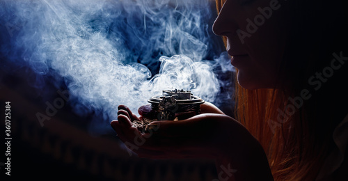 Obraz na płótnie incense in a woman hand, incense smoke on a black background.