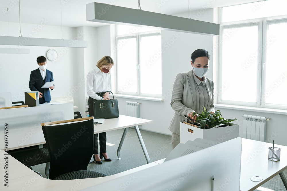 Young office workers in formalwear and protective masks standing by their desks Young office workers in formalwear and protective masks standing by their desks