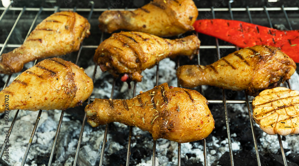 juicy golden grilled chicken legs on the grill, barbecue, coals
