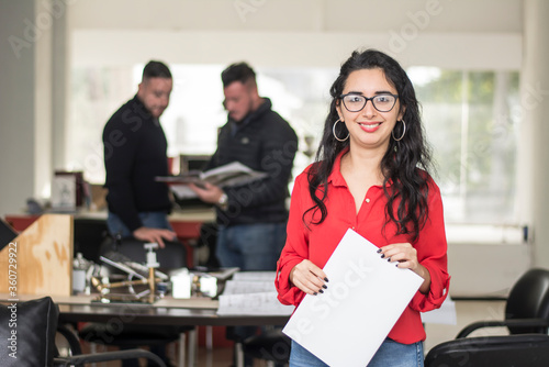 female real estate agent in the foreground holding a contract in her hands, businessmen in the background