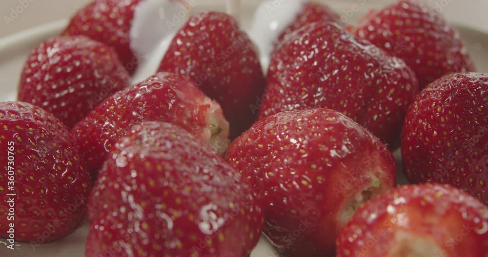 Fresh strawberries poured over yogurt, slow motion. Pouring yogurt onto strawberries. Fresh strawberries poured over yogurt, slow motion. Pouring yogurt onto strawberries.
