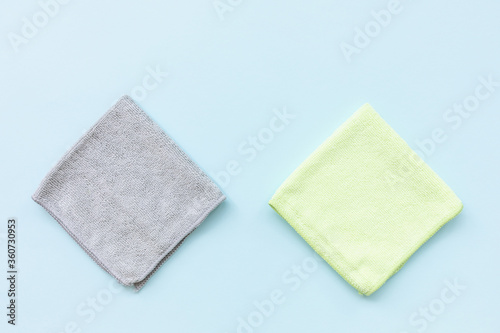 Two new folded microfiber cloth for cleaning on blue background. Cleaning micro fabric towels for dusting and polishing. Domestic household cleaning service concept. Top view, copy space