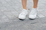 A person woman's legs in shoes standing on a sidewalk