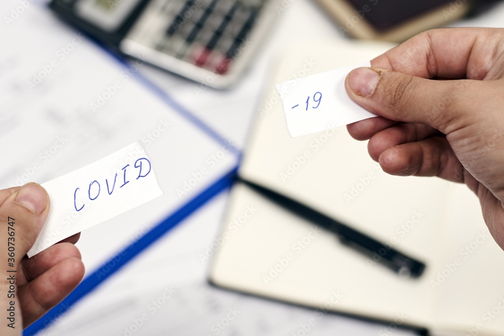 Man holding a torn piece of paper with the word "COVID-19" on it ...