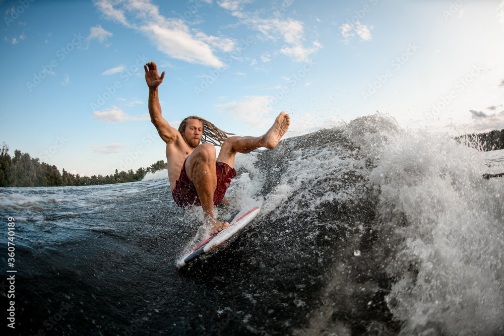young wakesurf man falls from board on wave.