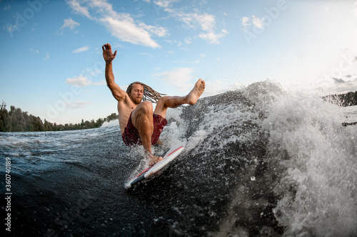 young wakesurf man falls from board on wave.